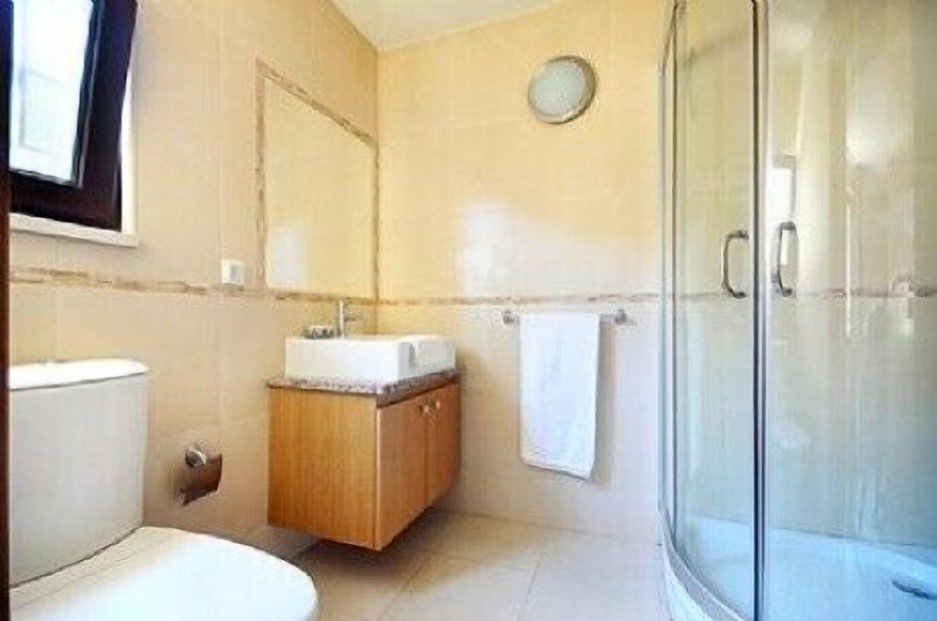 Ein Badezimmer mit Toilette, Waschbecken, Spiegel und Duschkabine.