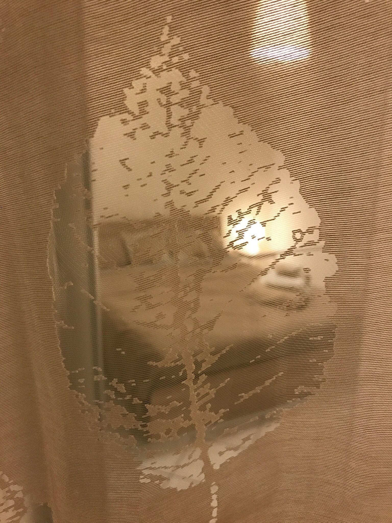 A textured fabric with a reflective surface, possibly a window or curtain.