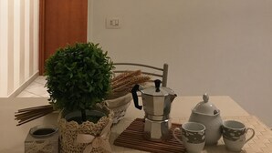 Ein Zimmer mit einer Wanduhr, einem kleinen Tisch, einer Teekanne, Tassen und einer Topfpflanze.