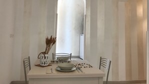 Ein Essbereich mit einem Tisch für zwei Personen, einer weißen Vase mit Trockenpflanzen und einem weißen Luftreiniger.