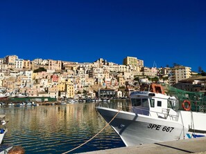 Un port avec un bateau amarré au premier plan et une colline densément bâtie en arrière-plan.