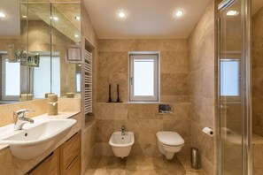 Een bad/douchecombinatie, een haardroger, een bidet, handdoeken