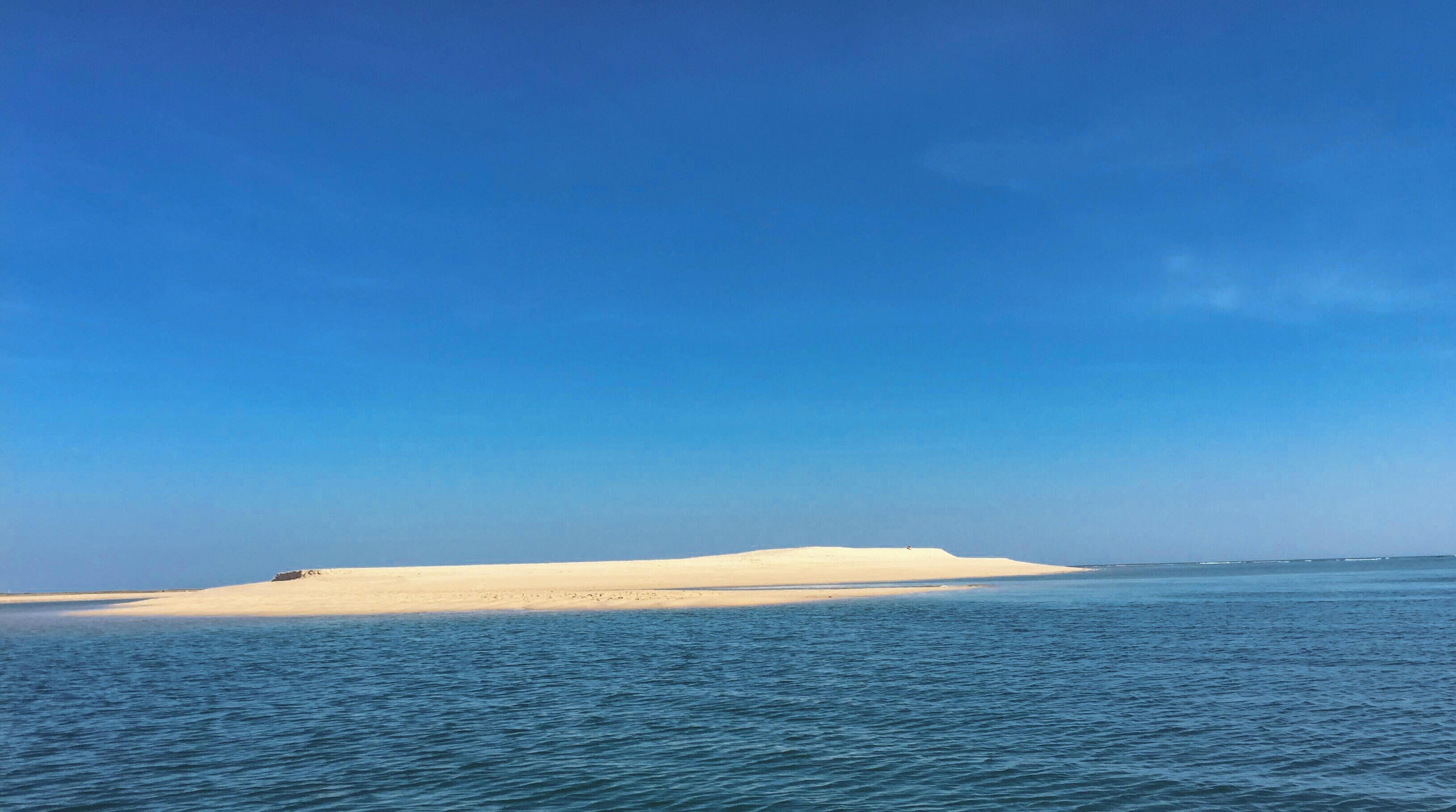 Una playa arenosa con agua tranquila y un cielo despejado.