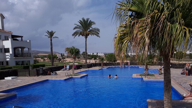 A swimming pool with clear blue water, surrounded by palm trees and a fenced area. - Hacienda Riquelme Polaris World Golf / Holiday Resort, Sucina, Spain  (Murcia)
