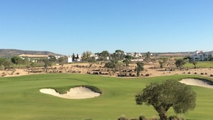 A golf course with sand bunkers, a clear sky, and distant buildings. - Hacienda Riquelme Polaris World Golf / Holiday Resort, Sucina, Spain  (Murcia)