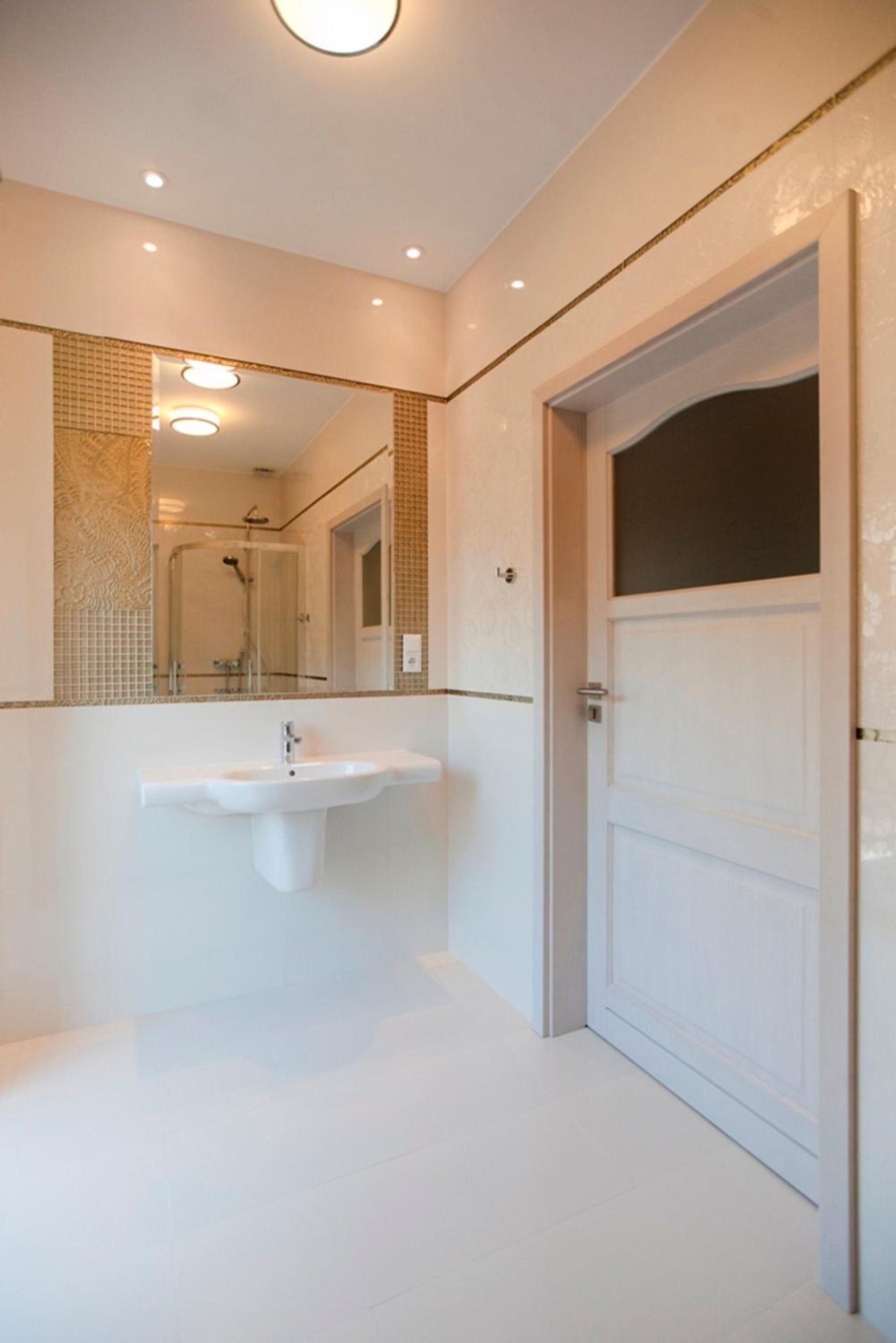 A bathroom with a white sink, a large mirror, and a door.