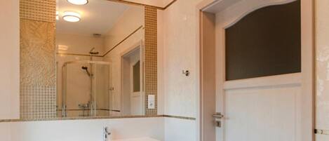 A bathroom with a white sink, a large mirror, and a door.
