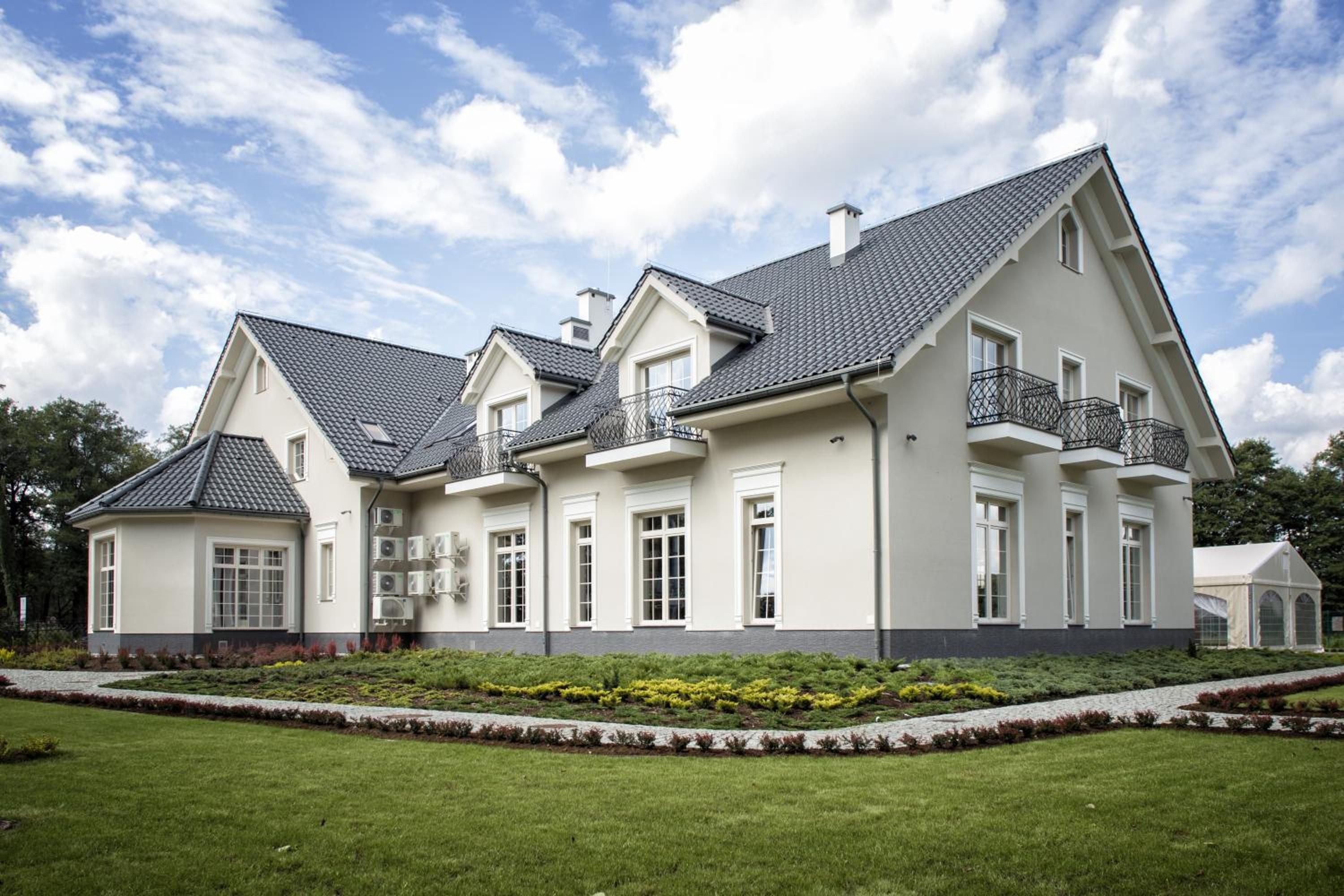 A large, two-story house with a symmetrical facade, multiple windows, and a well-maintained lawn.