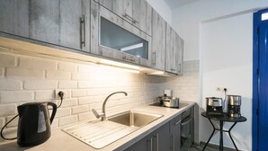 A modern kitchen with grey cabinets, a stainless steel sink, and a coffee machine on a small table. - sunset home crete 1  (heraklion)