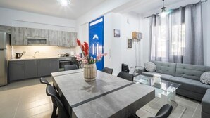 A modern kitchen with grey cabinets, a dining table with chairs, and a blue door. - sunset home crete 1  (heraklion)