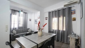A modern living room with a grey sofa, a dining table with chairs, and a small wooden cabinet. - sunset home crete 1  (heraklion)