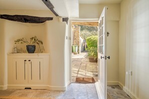 A hallway with a white door leading to an outdoor stone patio.