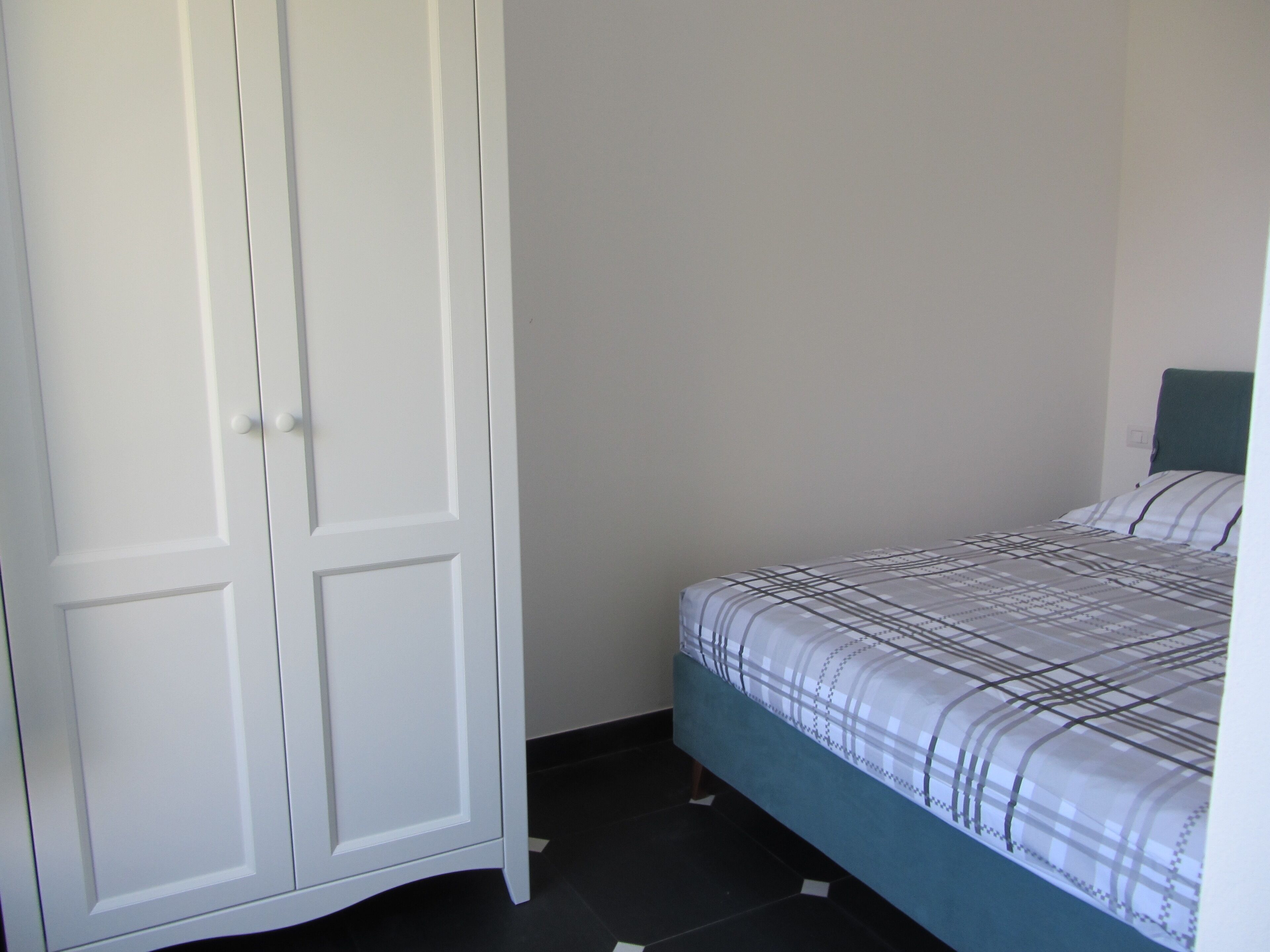 Una camera da letto con un letto, un armadio e una parete spoglia.