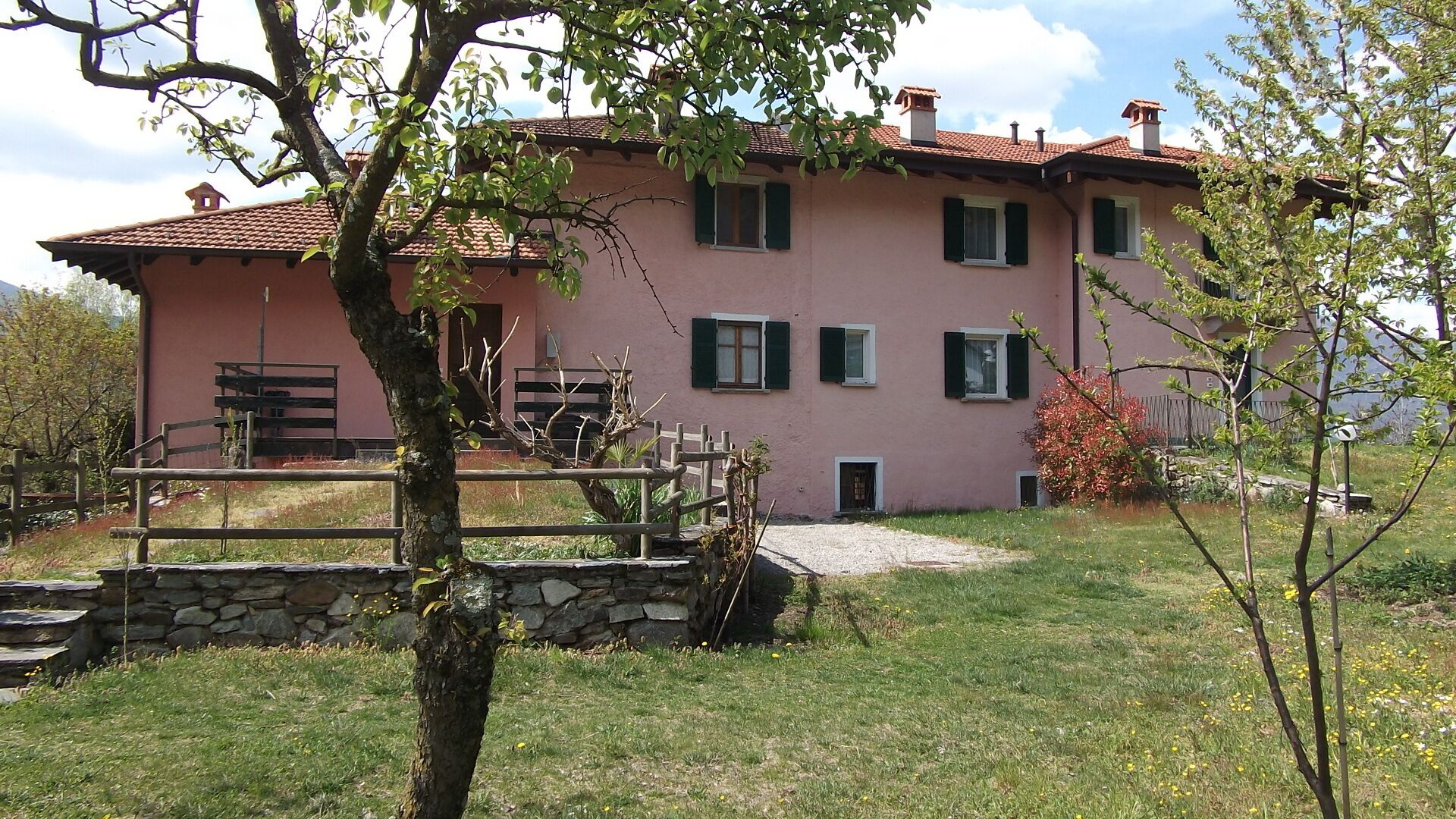 Un bâtiment rose avec un escalier en pierre menant à une terrasse en bois.