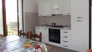 Uma cozinha compacta com armários brancos, fogão e lava-louças.