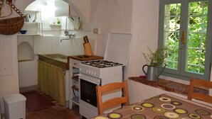 Une cuisine compacte équipée d’une cuisinière à gaz, d’un four et d’une fenêtre donnant sur un espace verdoyant.