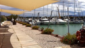 A marina with boats docked under large canopies, a wooden deck, and a rocky shoreline with some greenery. - Tuscany, an agrotourism apartment between sea and countryside. (Cecina)
