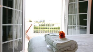 A hotel room with a bed, a window with curtains, and a view of a green landscape. - Luxury V5 | Pool & Jacuzzi | Beach 20 minutes walk | Groups & Families (Albufeira)