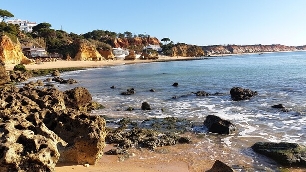 A coastal beach with rocky formations, clear blue water, and houses on the hillside. - Luxury V5 | Pool & Jacuzzi | Beach 20 minutes walk | Groups & Families (Albufeira)