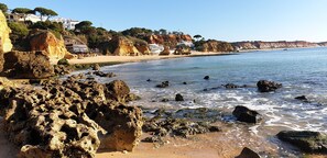 A coastal beach with rocky formations, clear blue water, and houses on the hillside. - Luxury V5 | Pool & Hot Tub | Beach 20 minutes away on foot | Groups & Families (Albufeira)