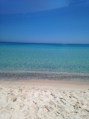 A beach with clear turquoise water and a sandy shore.
