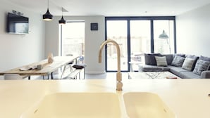 A modern kitchen with a central island, pendant lighting, and a large window.
