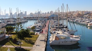 A marina with numerous boats docked, a clear sky, and a cityscape in the background. - Modern apartment with great pool, next to harbour, boulevard and beach (el Campello)