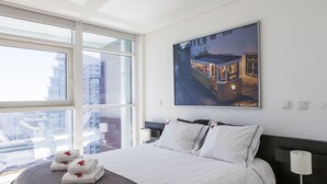 A hotel room with a large bed, a city view, and a framed picture on the wall. - RENT4REST LISBON PARQUE DAS NAÇÕES 17TH FLOOR RIVER VIEW (Lisboa ciudad)