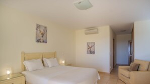 A bedroom with a large bed, bedside tables, a nightstand, a sofa, and two wall-mounted air conditioning units. - Estrela da Luz Spectacular Penthouse With Sea And Pool View (Luz)