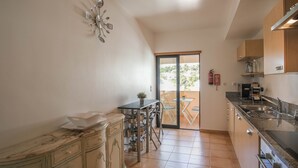 A kitchen with a marble countertop, a sink, and a dining area with a table and chairs. - Estrela da Luz Spectacular Penthouse With Sea And Pool View (Luz)