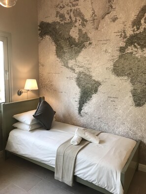 Cozy retreat with a single bed, vintage map, and soft lighting.