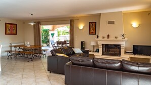 A living room with a fireplace, leather sofa, dining table, and a view of the outdoor patio. - House / Villa - DRAGUIGNAN (Draguignan)