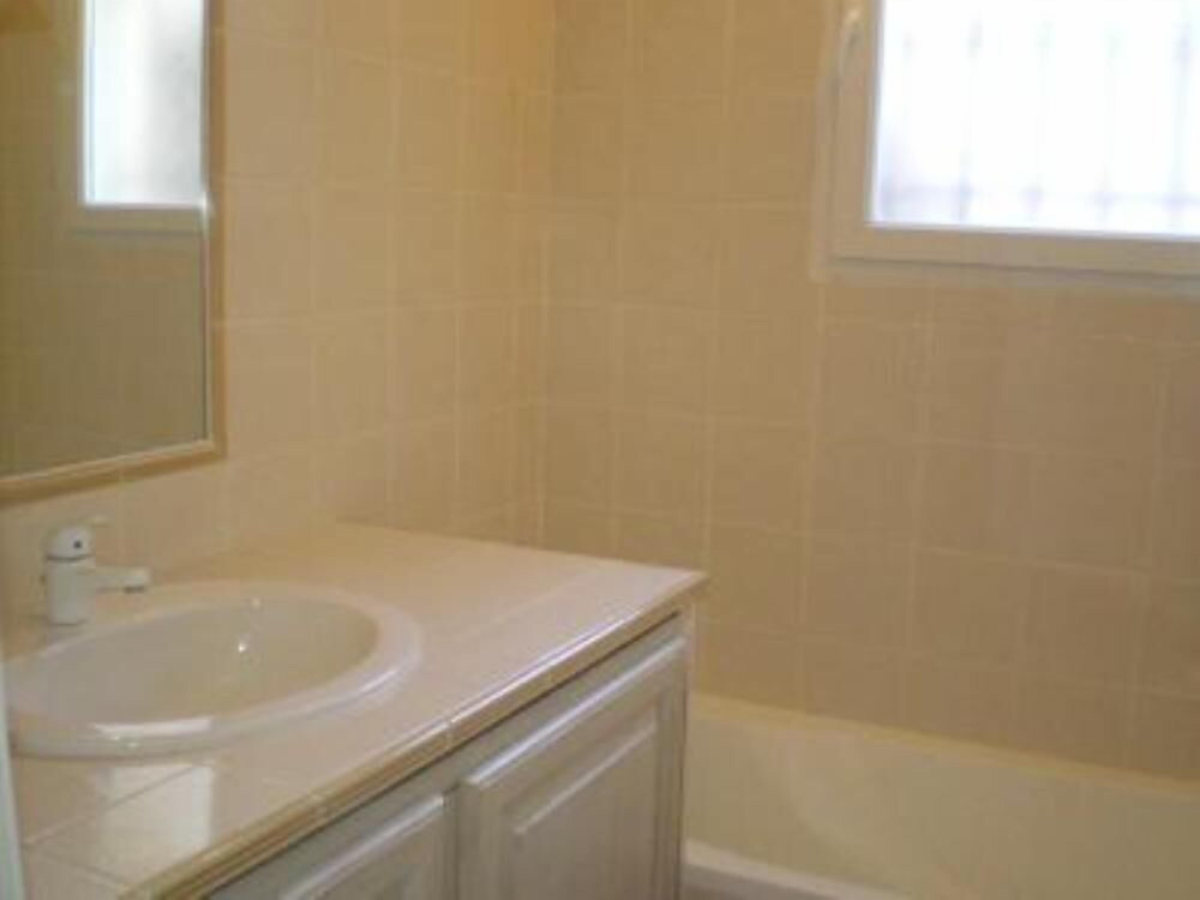 A bathroom with a sink, mirror, and bathtub.
