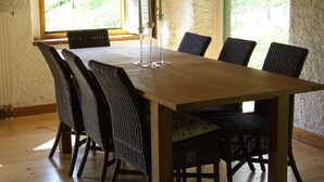 A dining table with six chairs, a window with a view of greenery, and a lamp on the table. - Farmhouse in Klavze, Most na Soci, Primorska, Slovenia - Peaceful Location (Klavže)