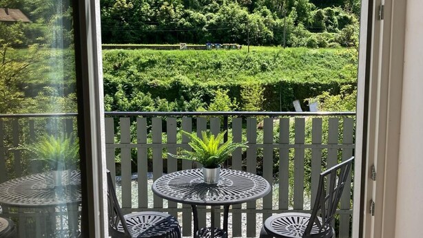 A balcony with a view of a lush green landscape, a small round table with chairs, and a potted plant. - Farmhouse in Klavze, Most na Soci, Primorska, Slovenia - Peaceful Location (Klavže)