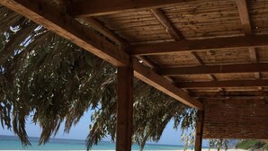 A beachside cafe with metal chairs and tables, overlooking a sandy beach and the ocean. - Calaverde, very refined apartment a stone's throw from the sea (Pula)