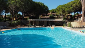 A swimming pool with clear blue water, surrounded by trees and buildings. - Calaverde, very refined apartment a stone's throw from the sea (Pula)