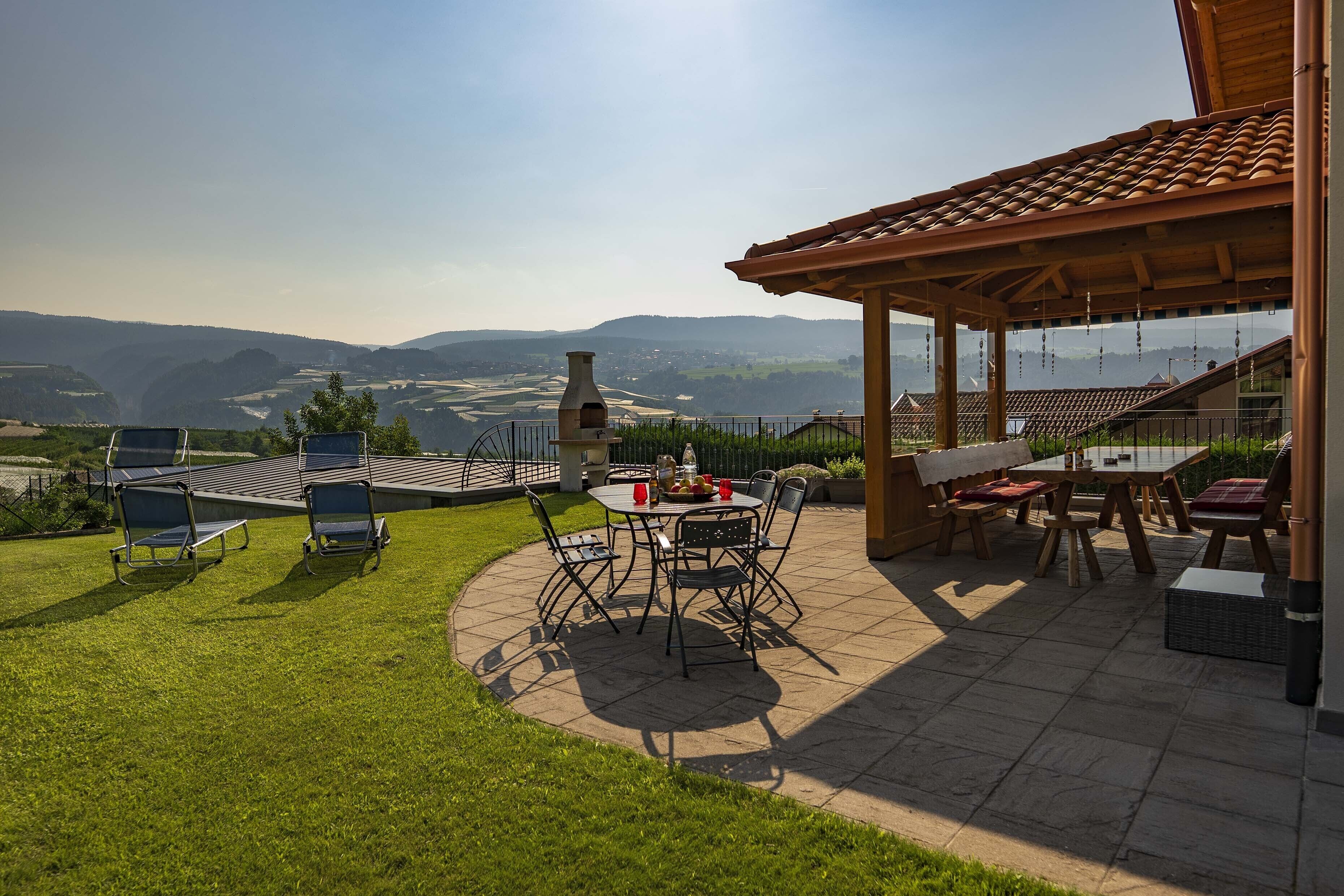 A patio with outdoor furniture, a barbecue grill, and a view of the countryside.