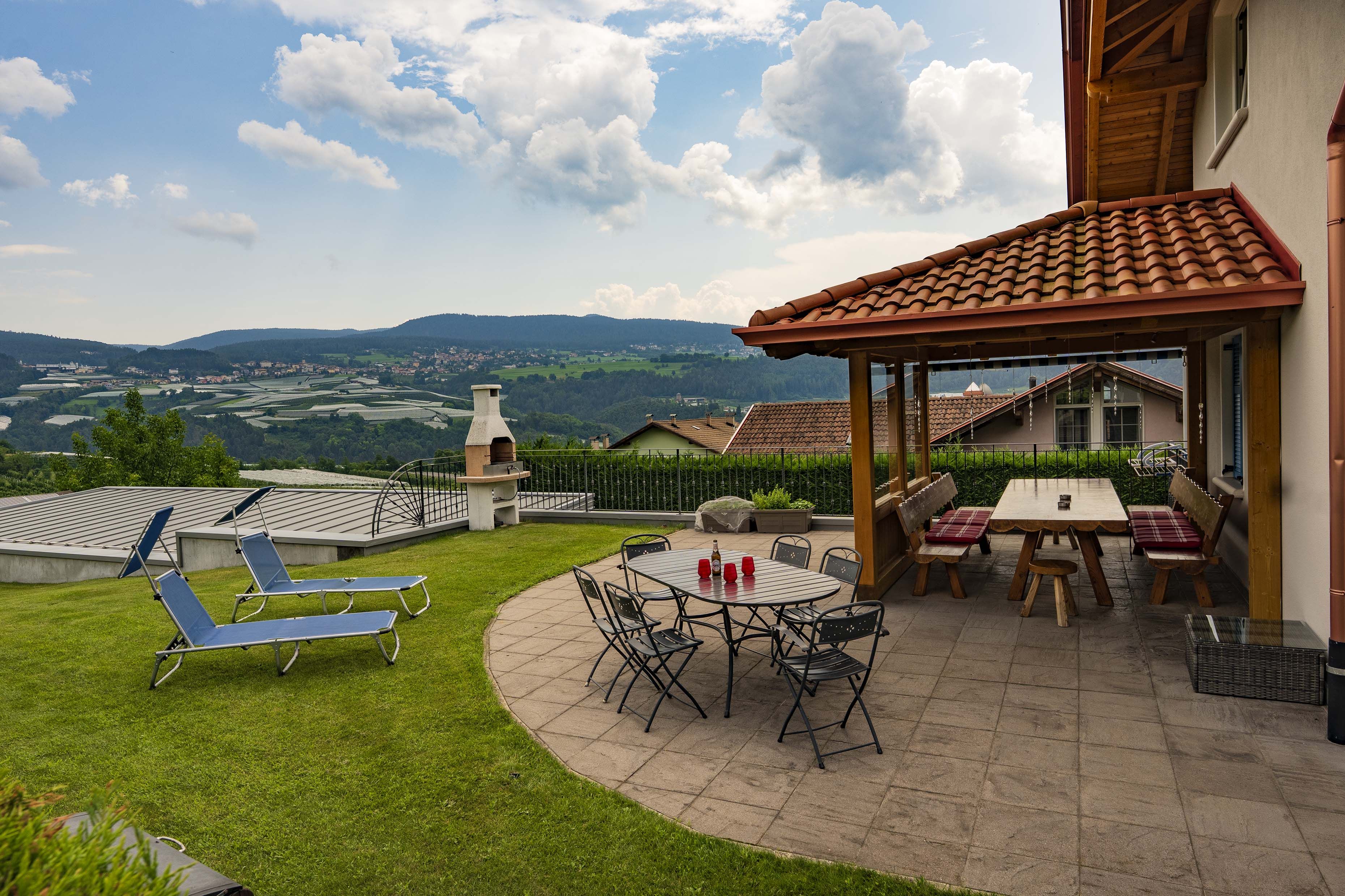 Une terrasse avec une table et des chaises, un barbecue et une vue sur la campagne.