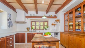 A kitchen with wooden cabinets, a wooden table, and a hanging light fixture. - SES VELLETES 7 - Villa with private pool in Artà. (Artà)