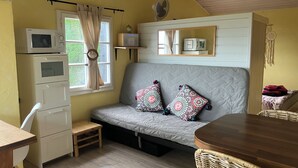 A cozy room with a sofa, a small table, a microwave, and a television.