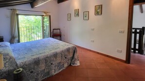 A bedroom with a bed, a chair, and a balcony with a view of greenery. - Romantic Riverside Property, small private pool. WIFI . Walk to facilities (Borsigliana)