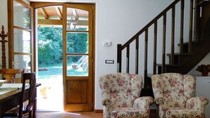 A dining area with a wooden table and chairs, a wooden staircase, and two floral armchairs. - Romantic Riverside Property, small private pool. WIFI . Walk to facilities (Borsigliana)