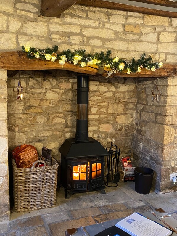 Cozy space with a stone wall, black wood-burning stove, and rustic charm.