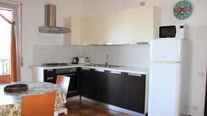 Una cocina con estufa, microondas, pileta y alacenas.