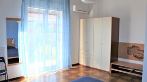 Una habitación con cama, escritorio, armario y banca.