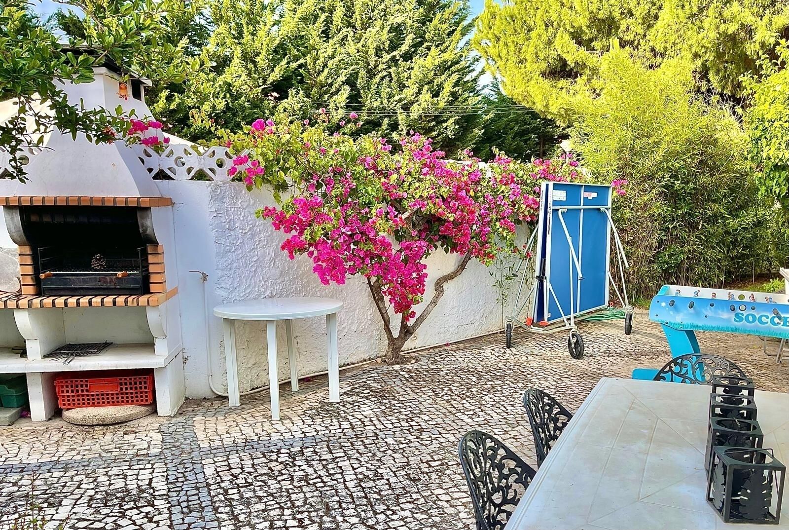 An outdoor patio with a barbecue grill, a small table, and a blue bench.