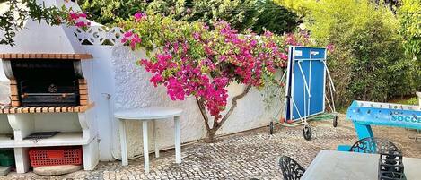 An outdoor patio with a barbecue grill, a small table, and a blue bench.