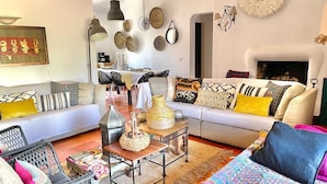 Een woonkamer met een bank, stoelen, een salontafel en een open haard.