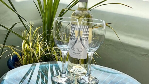 A bottle of VICELO wine and two glasses on a balcony with a view of buildings and greenery. - Roof Terrace Beach at end of road, Private Parking (Portsmouth)